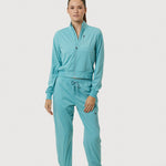 Person wearing a teal tracksuit on a white background
