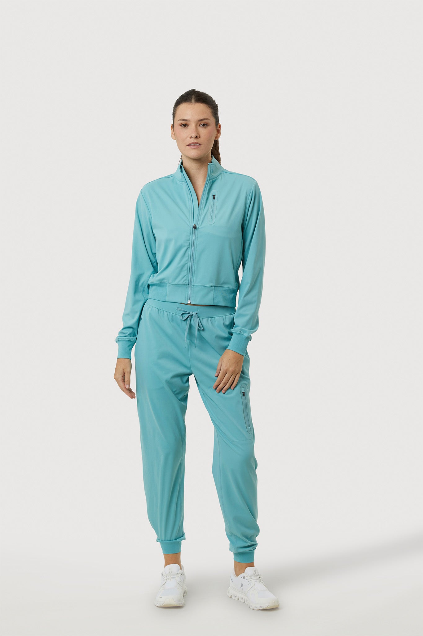 Person wearing a teal tracksuit on a white background