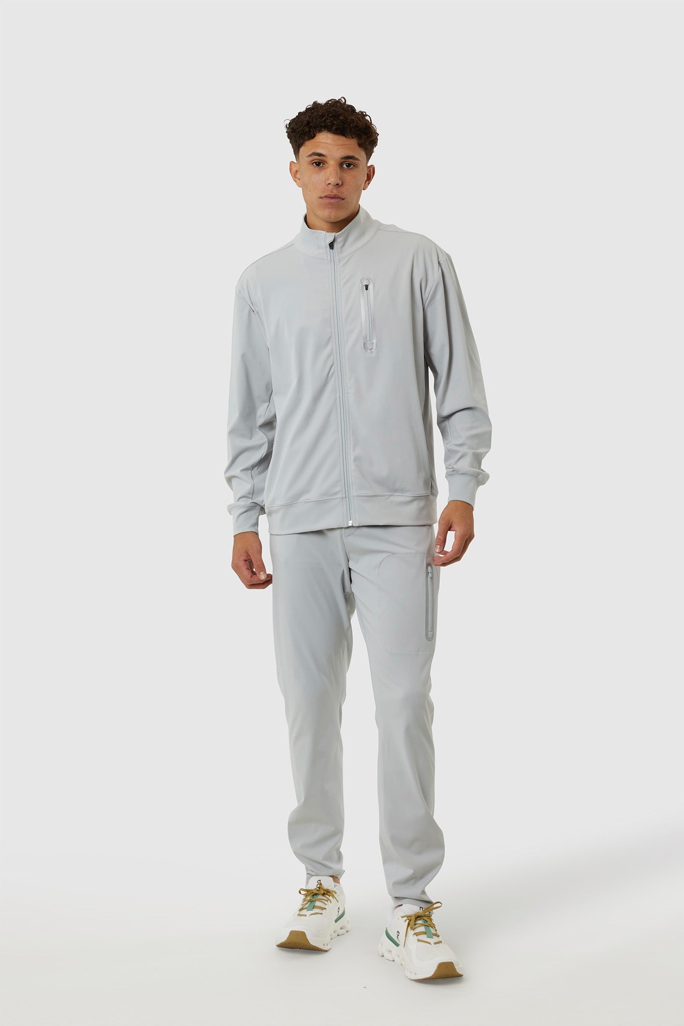 Person wearing a gray tracksuit on a white background