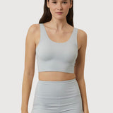 Woman wearing a light gray sports bra and shorts set on a white background