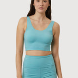 Woman wearing a teal sports bra and shorts set on a white background