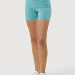 Person wearing turquoise shorts and white sneakers on a white background