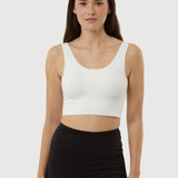 Woman wearing a white tank top and black shorts on a plain background