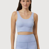 Woman wearing a light blue sports bra and shorts set on a plain background