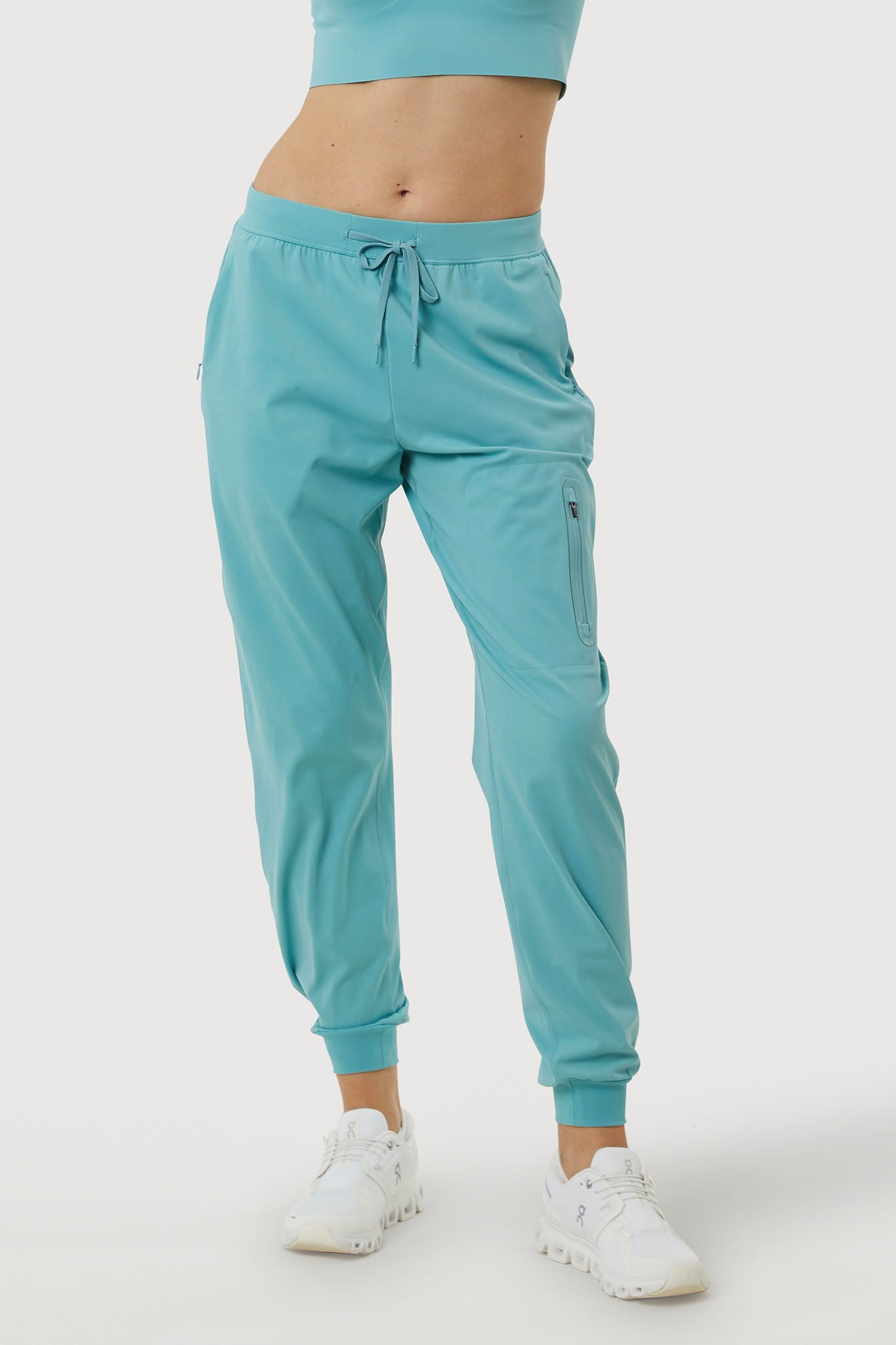 Teal jogger pants worn by a person on a white background