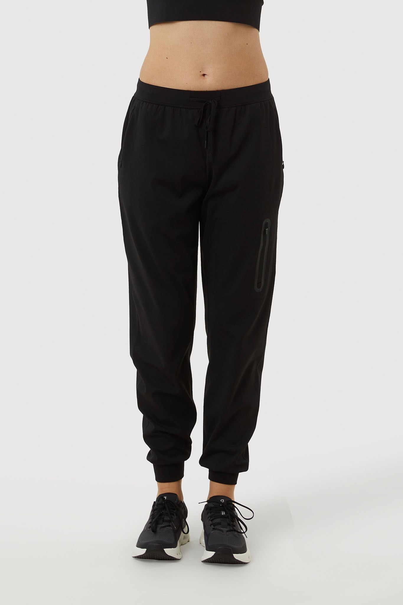 Person wearing black jogger pants on a white background