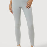 Person wearing light gray leggings and white sneakers on a plain background