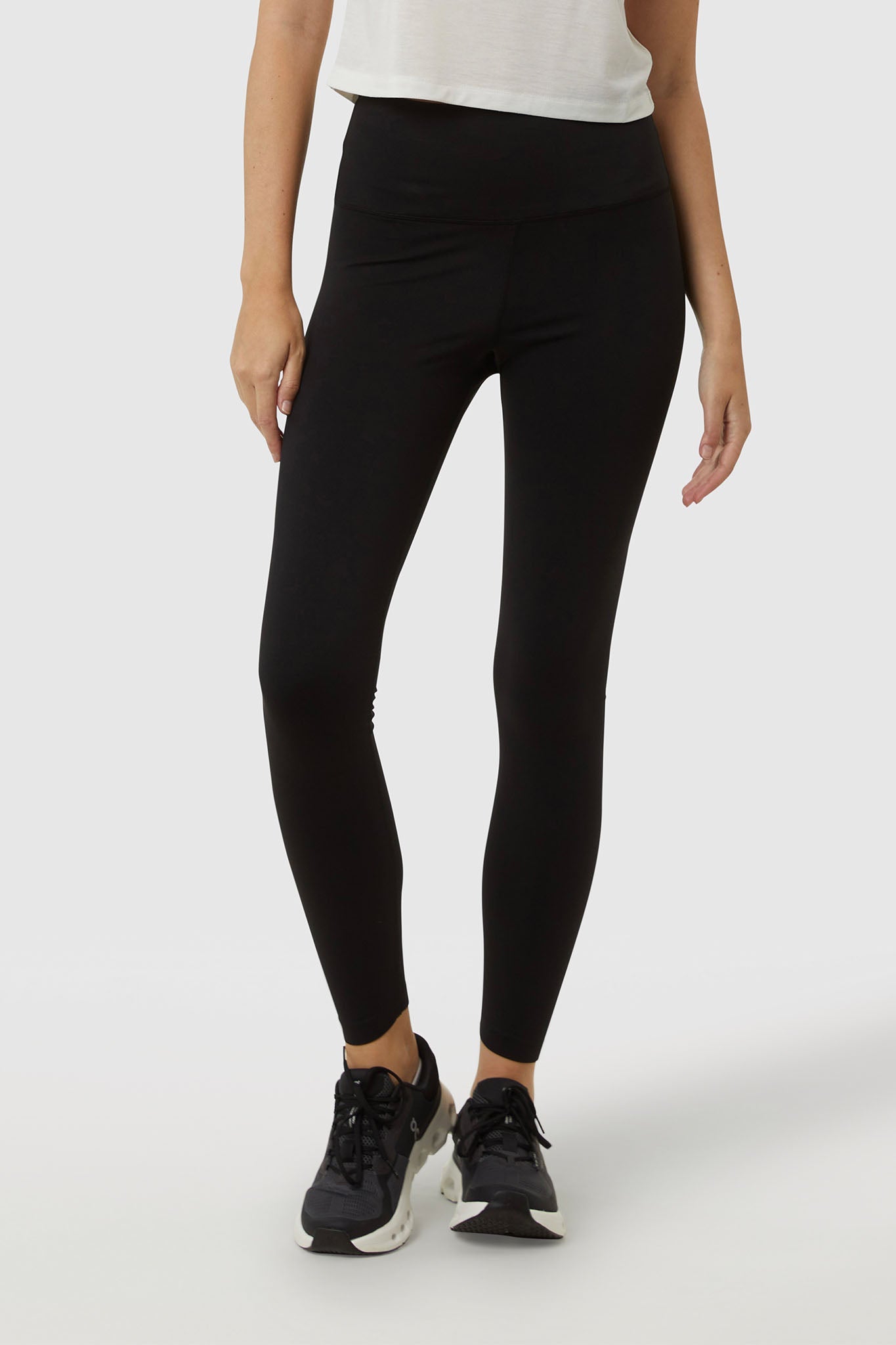 Person wearing black leggings and black sneakers on a white background