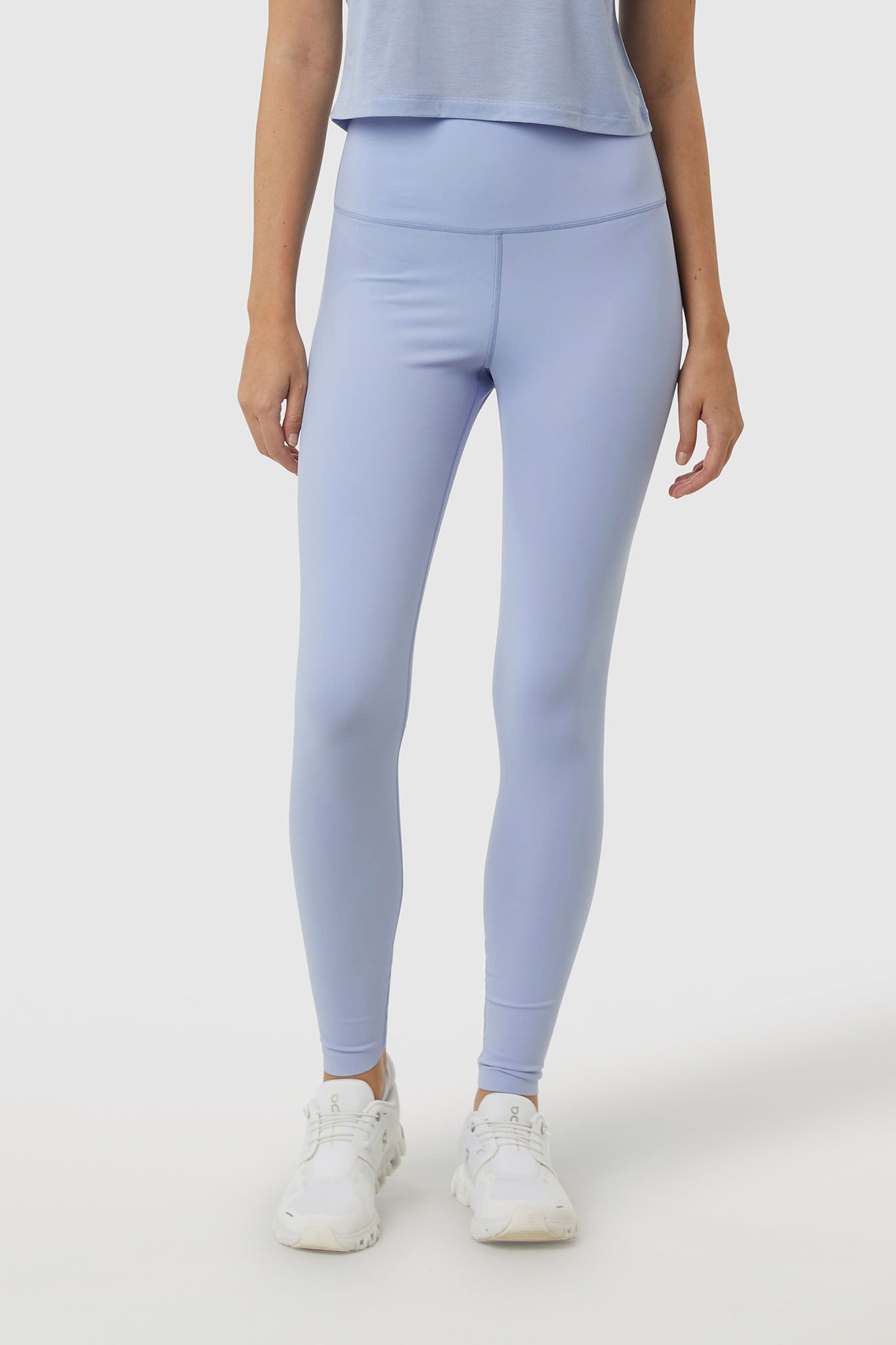 Person wearing light blue leggings and a matching top on a white background