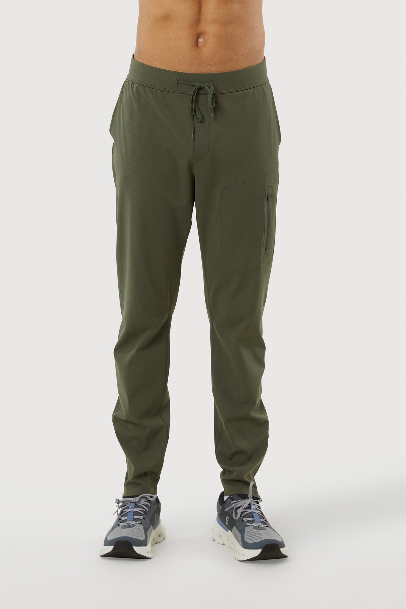 Person wearing olive green jogger pants on a white background
