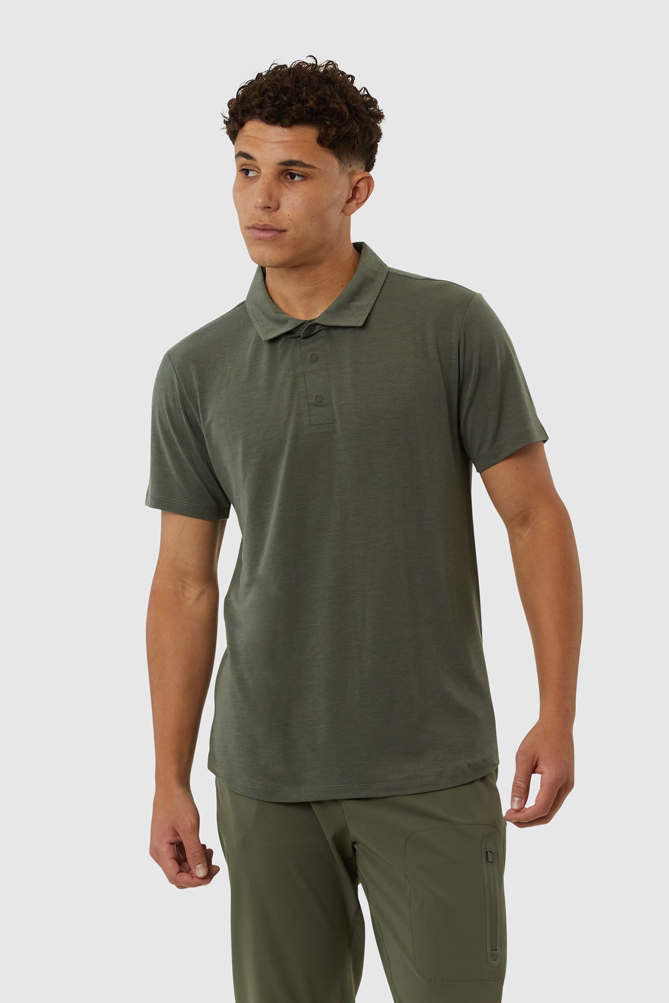 Man wearing a green polo shirt and pants on a white background