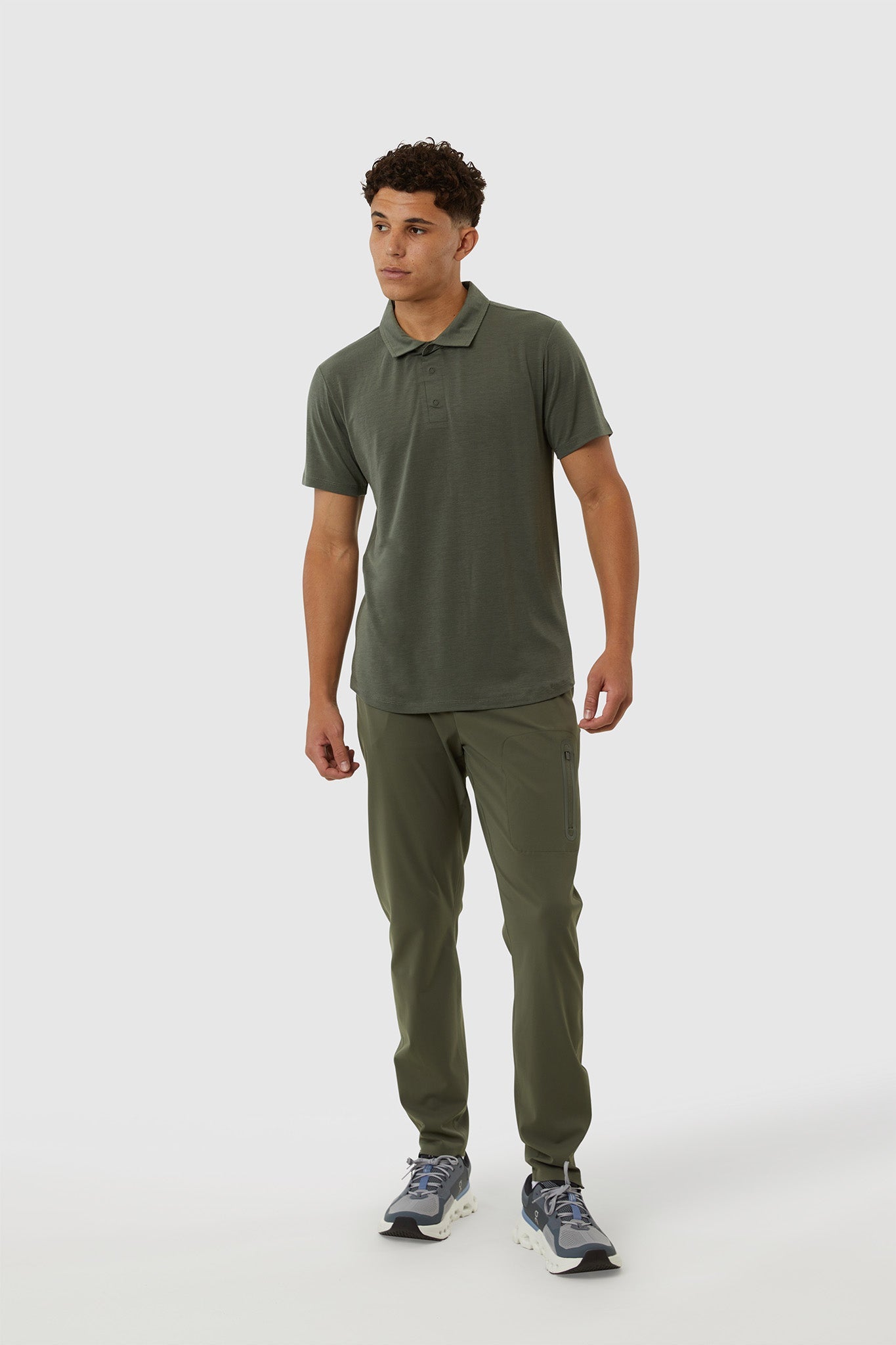 Man wearing a green polo shirt and pants on a white background