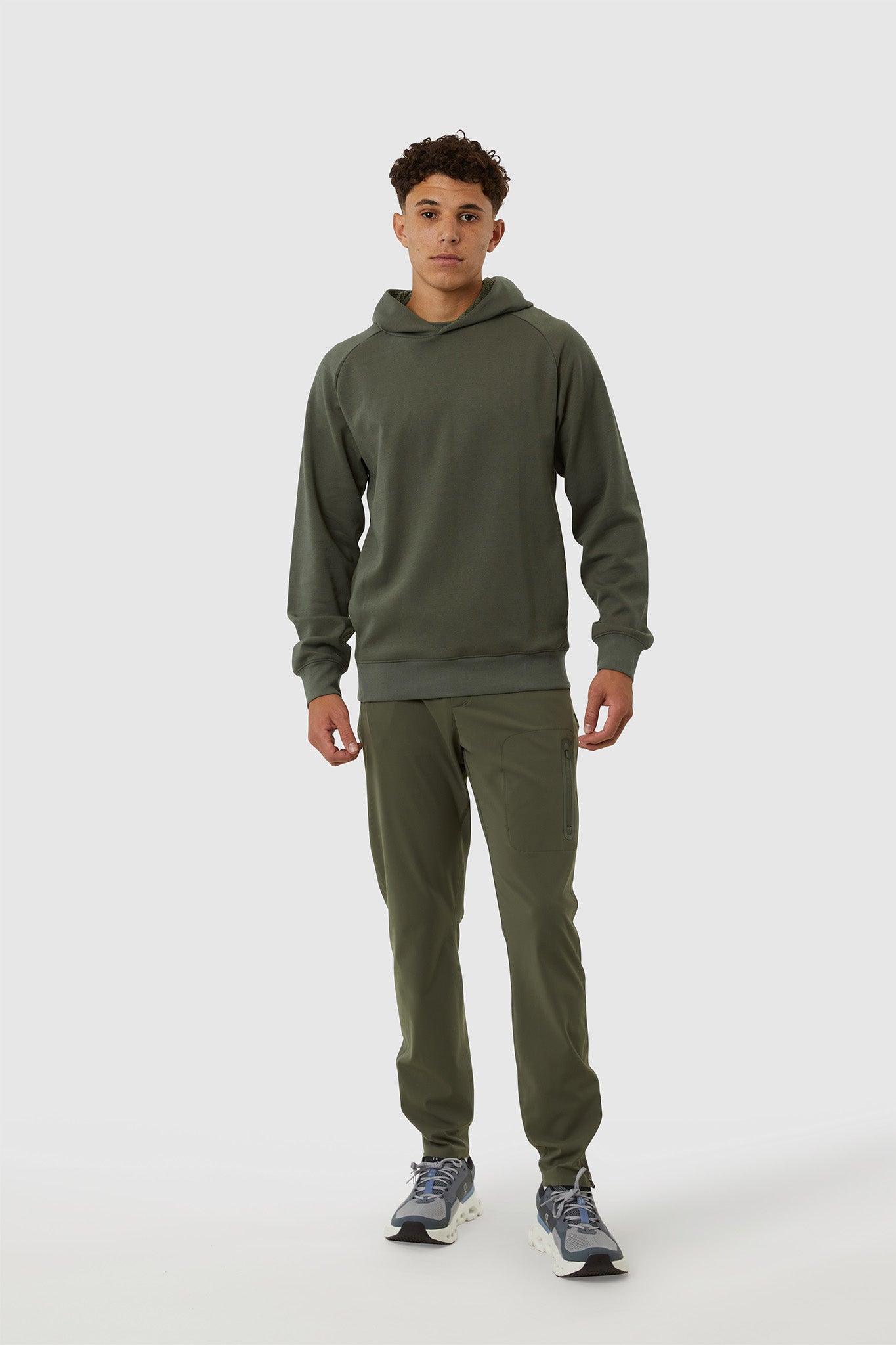 Person wearing a green hoodie and pants on a white background