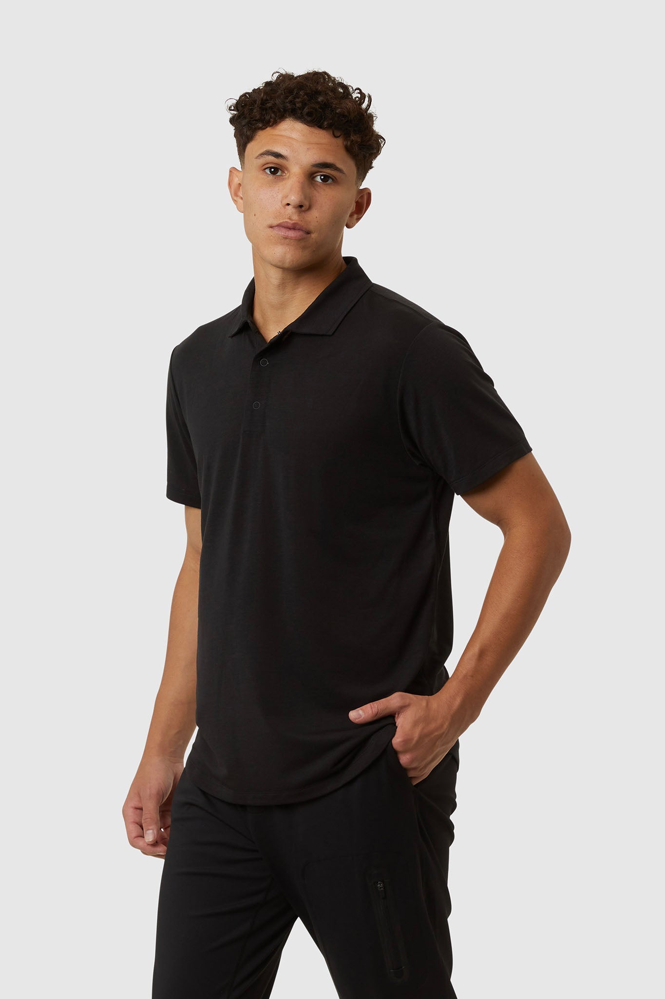 Man wearing a black polo shirt and pants on a white background