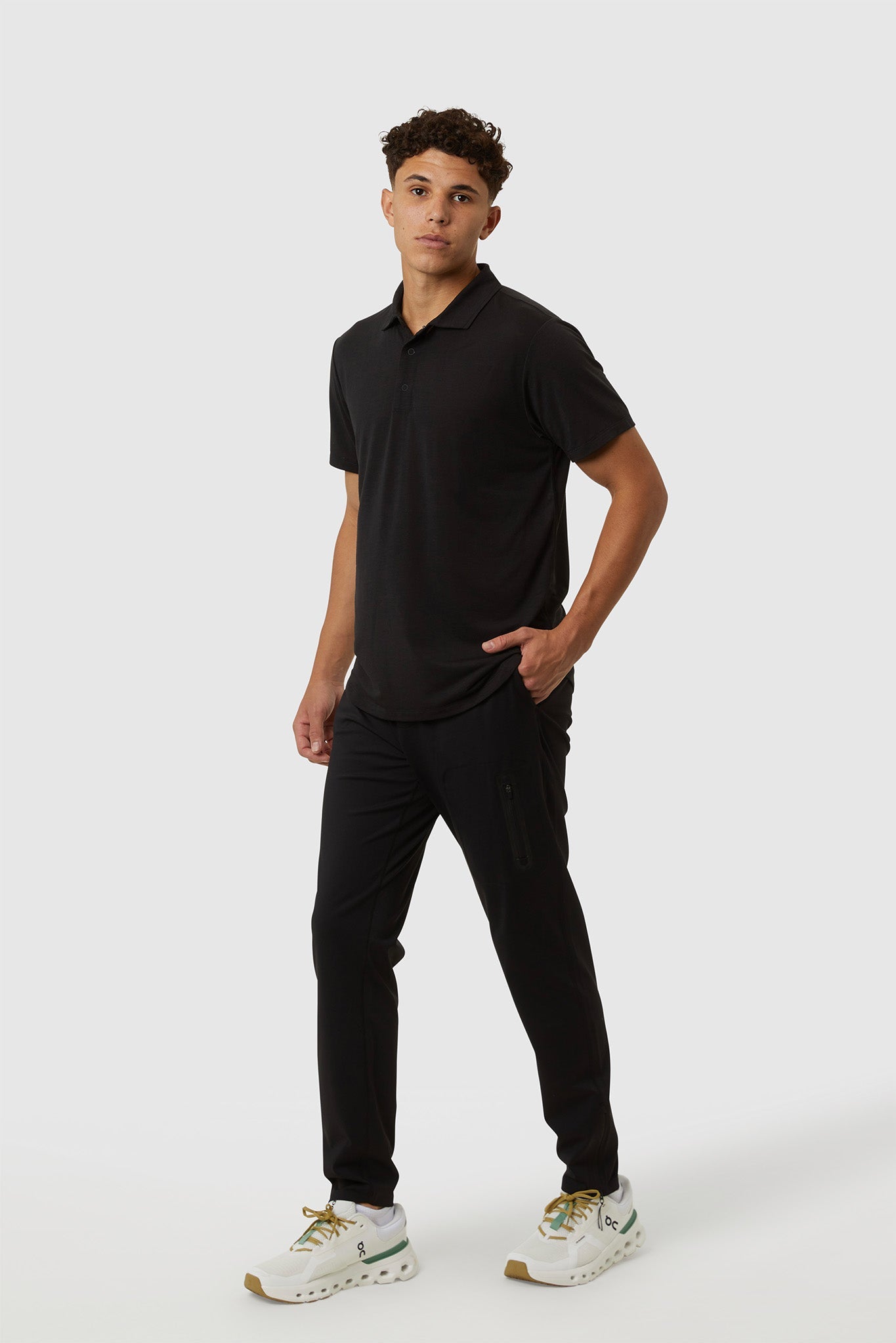 Man wearing a black polo shirt and pants on a white background