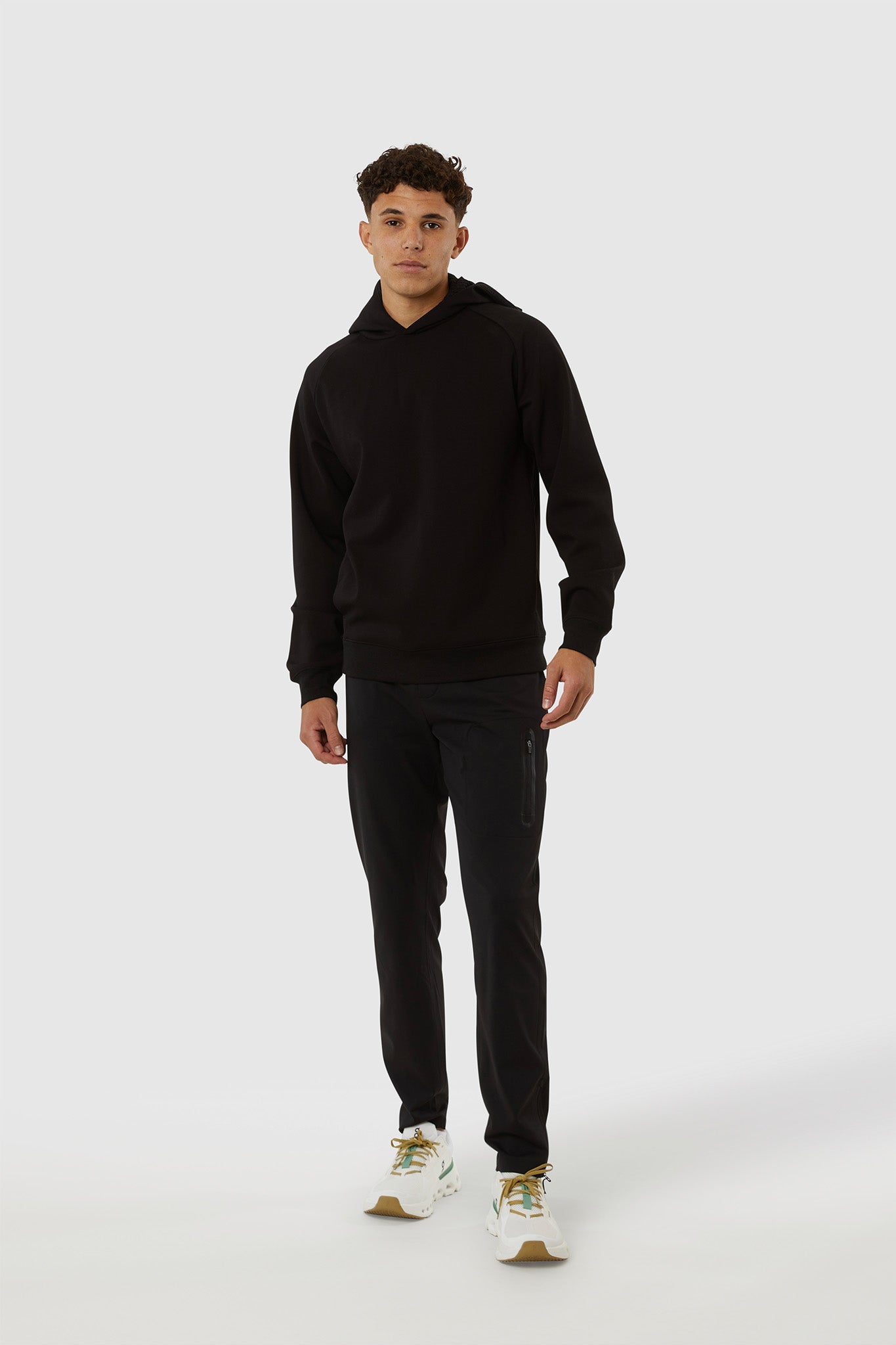 Person wearing a black hoodie and pants on a white background