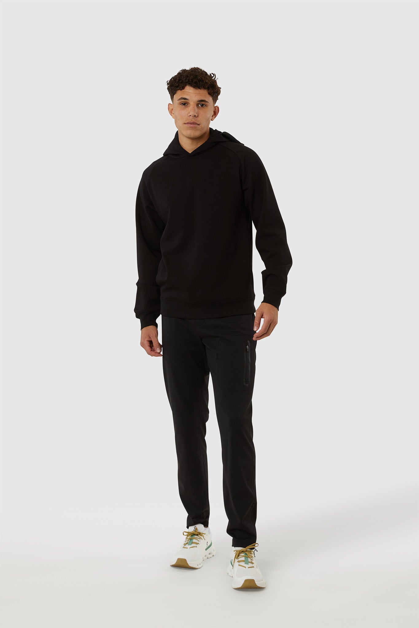 Person wearing a black hoodie and pants on a white background