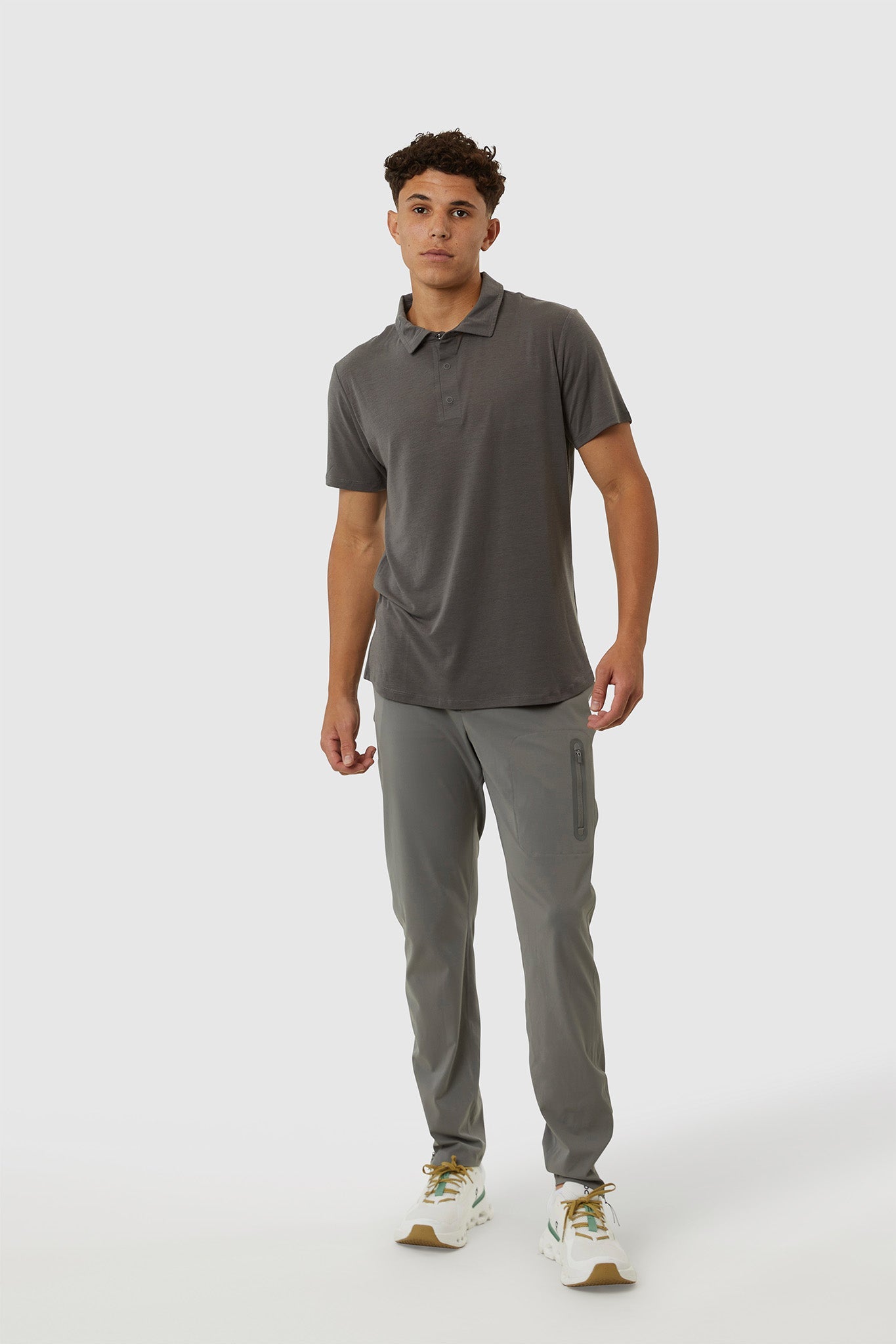 Man wearing a gray polo shirt and pants on a white background