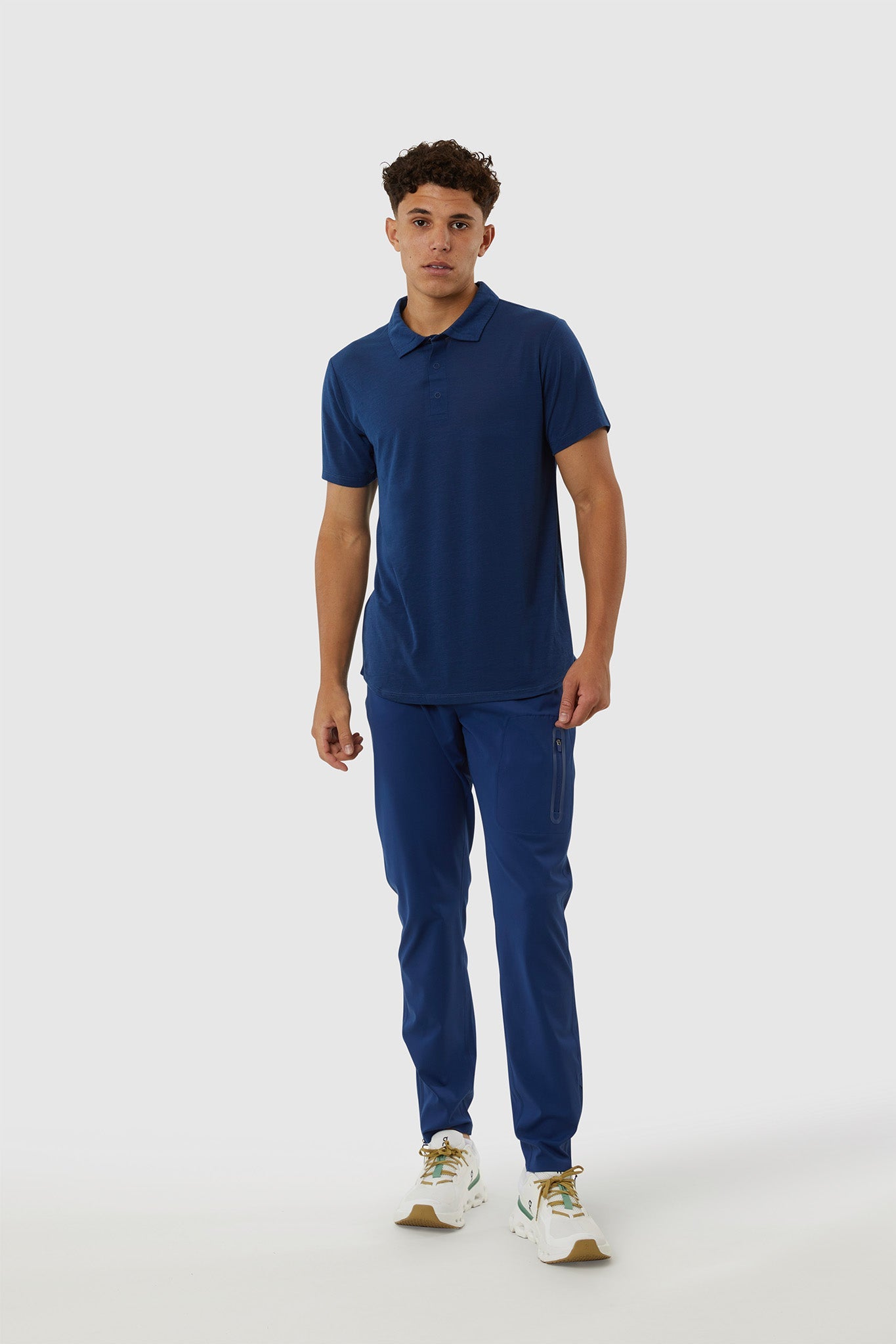 Man wearing a blue polo shirt and pants on a white background
