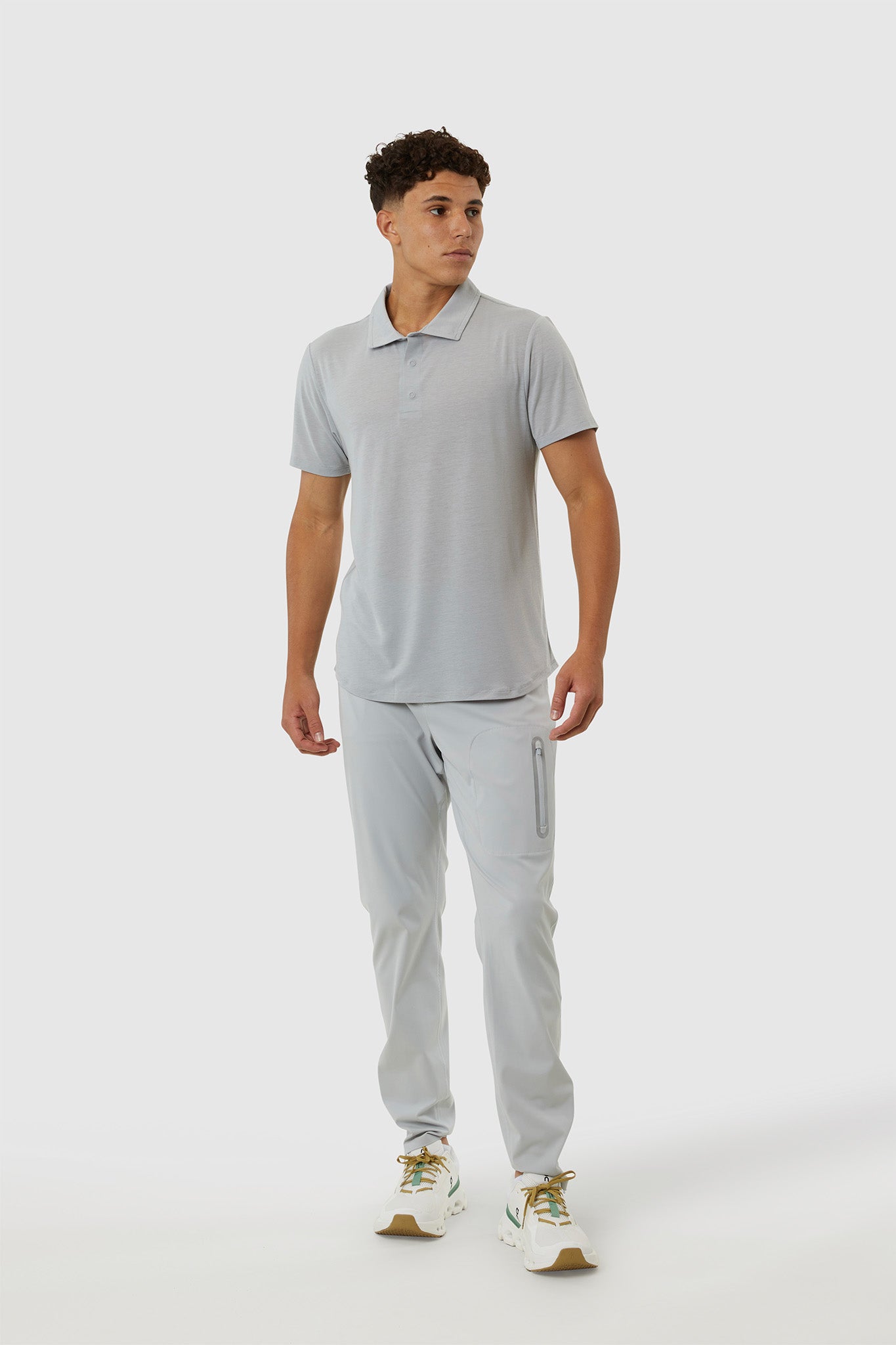 Man wearing a gray polo shirt and pants on a white background