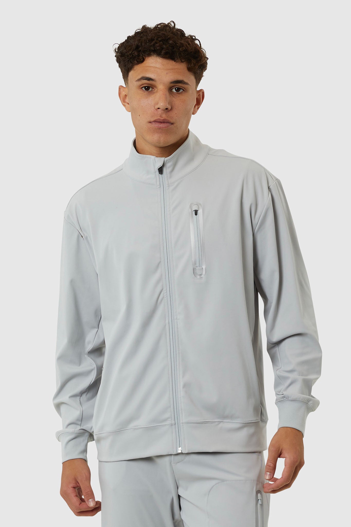 Man wearing a light gray tracksuit on a white background