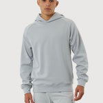 Person wearing a light gray hoodie and pants on a white background