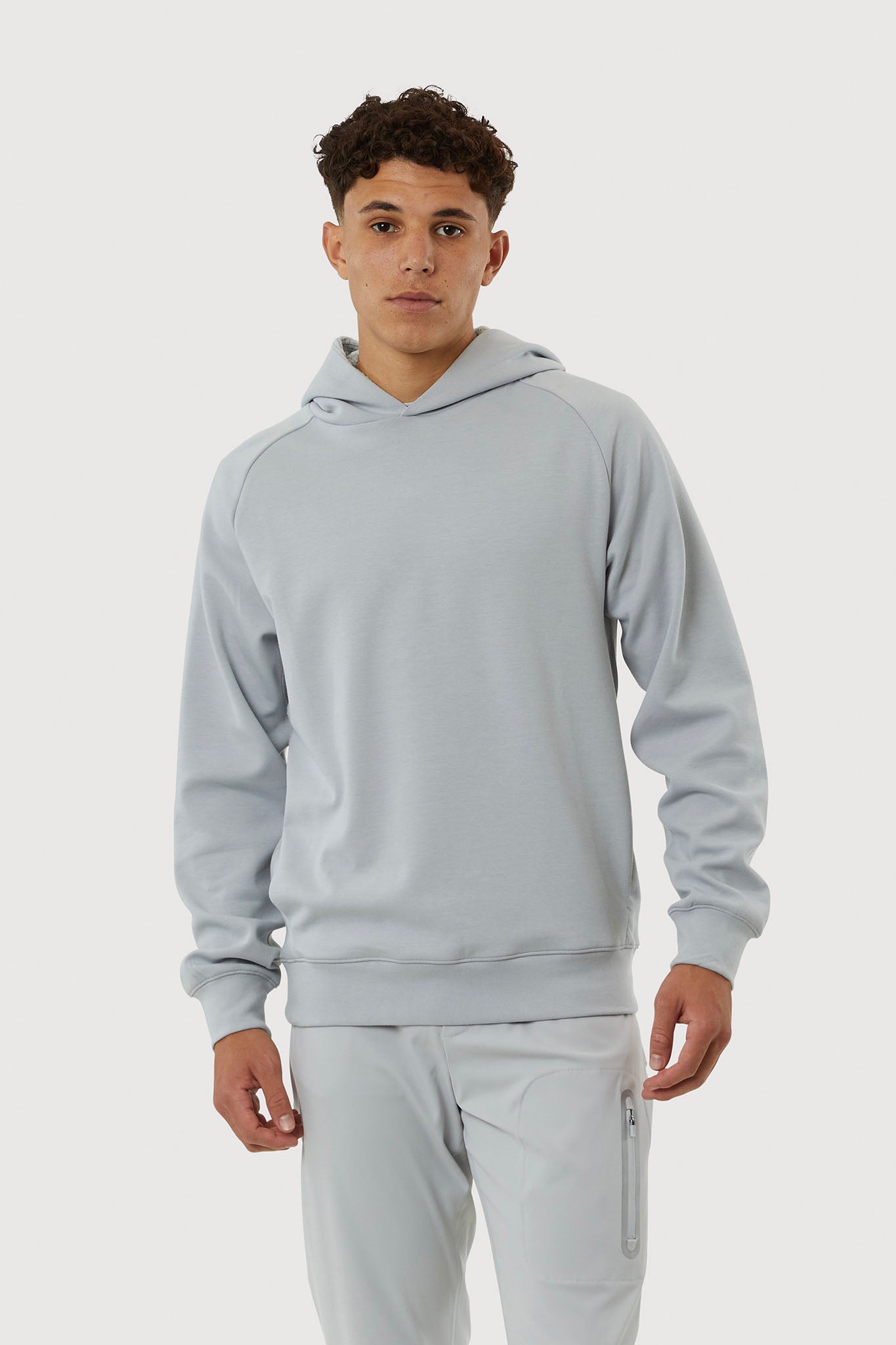 Person wearing a light gray hoodie and pants on a white background