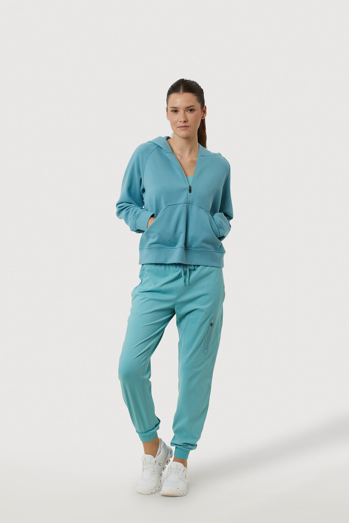 Woman wearing a teal tracksuit on a white background