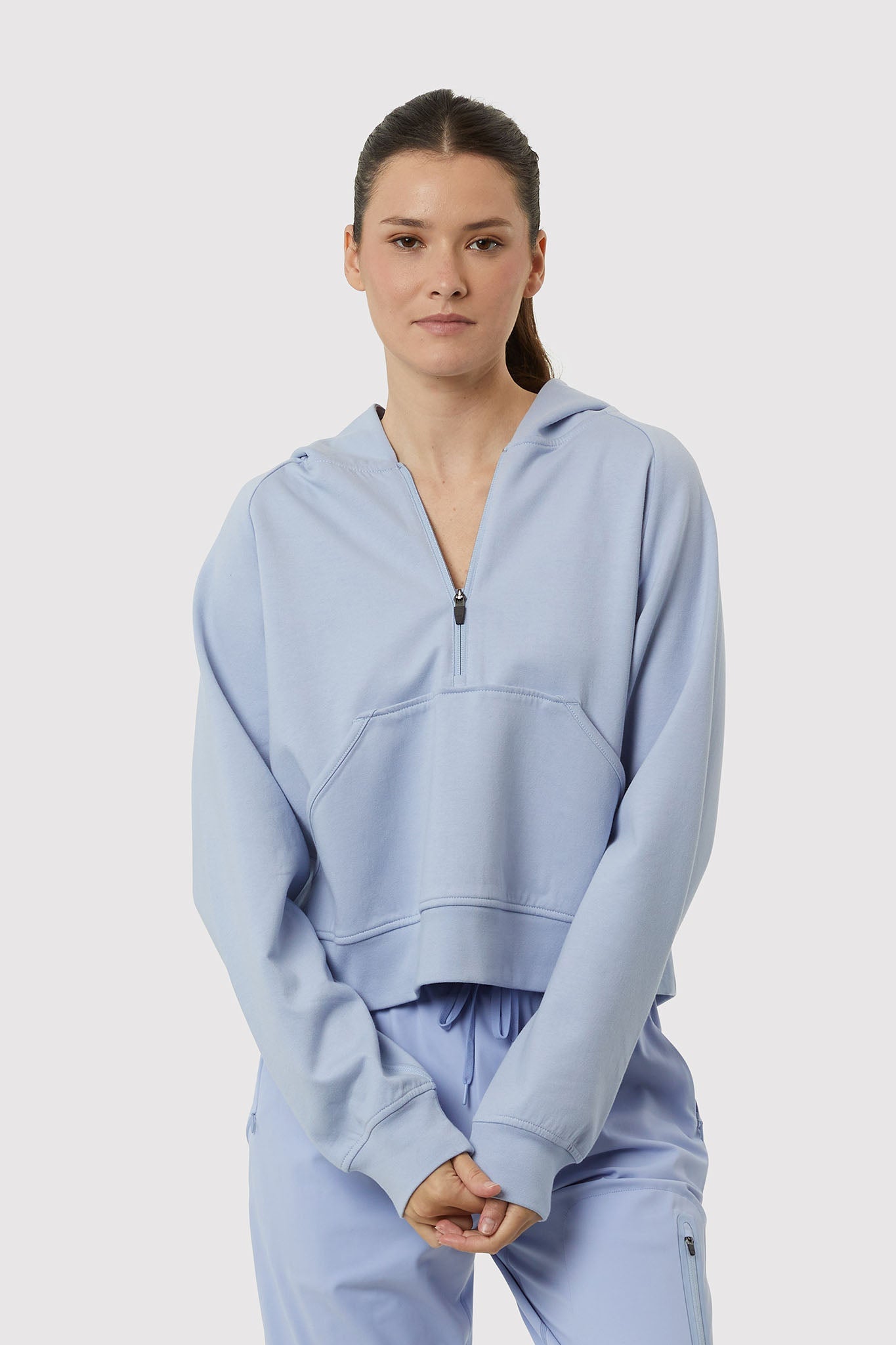 Person wearing a light blue hoodie and pants on a white background