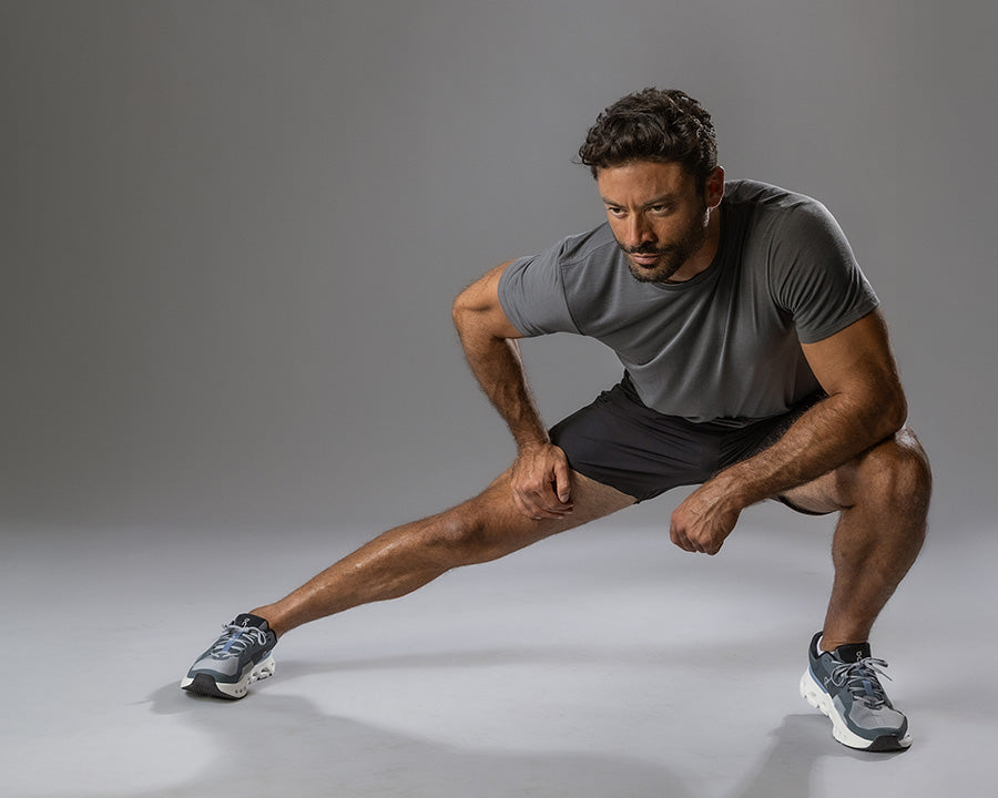 Man stretching his leg on a gray background