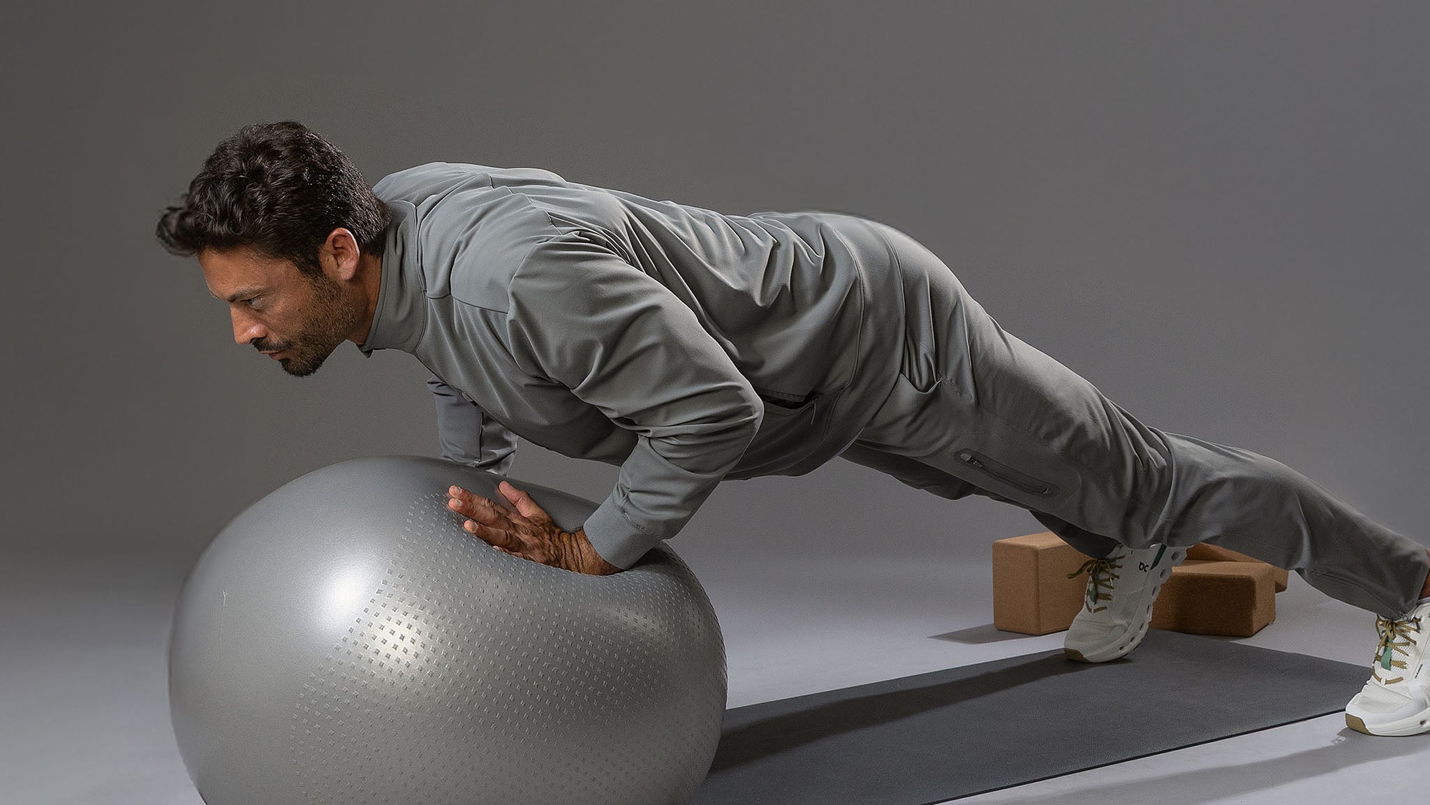 Man performing a push-up on an exercise ball with a neutral background
